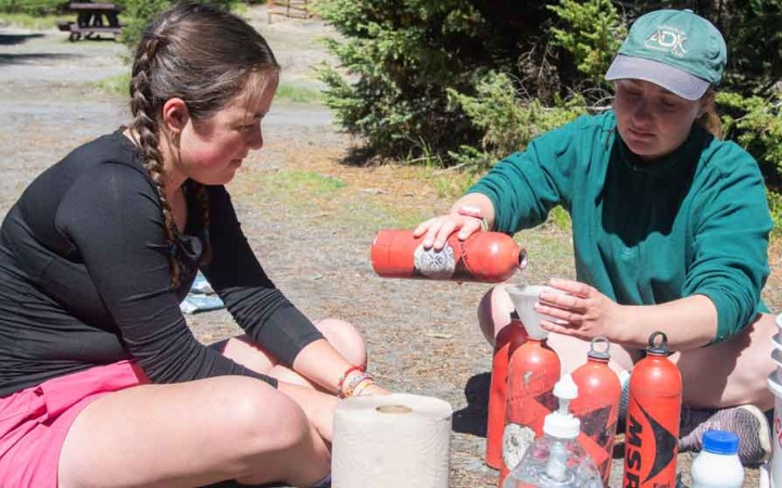 two teens fill up water bottles on backpacking expedition 